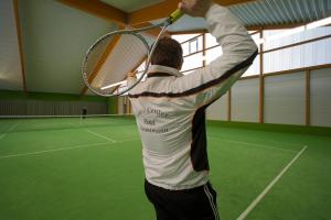 un hombre sosteniendo una raqueta de tenis en una pista de tenis en Hotel Hennemann, en Cobbenrode