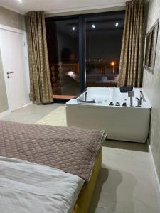 a bedroom with a bed and a tub with a view at Lux Vila Aleksandar in Sremska Kamenica +12 photos