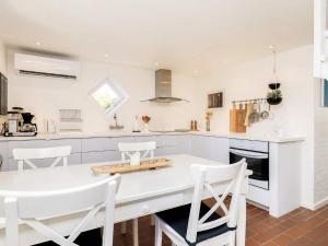 a kitchen with a white counter and white chairs at 4 person holiday home in Skagen in Skagen