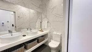 a white bathroom with two sinks and a toilet at MyTrip Porto in Matosinhos