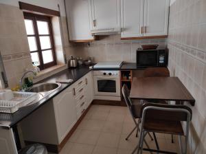 a kitchen with white cabinets and a sink and a table at Al Casa Paquito in Almograve