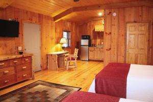 a bedroom with a bed and a kitchen with wooden walls at The Pineola in Newland