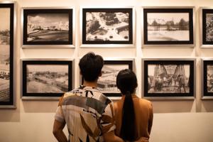 een man en een vrouw die naar een muur van foto's kijken bij The Bridge An Eclectic Luxotel in Chiang Mai