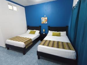 two beds in a room with blue walls at Posada Antonia Bacalar in Bacalar