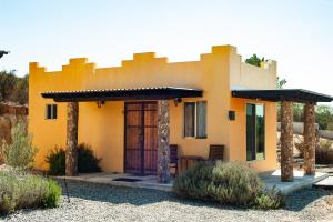 ein kleines gelbes Haus mit einer Veranda in der Wüste in der Unterkunft Quinta Estrella in Valle de Guadalupe