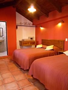 two beds in a room with red walls at Hotel Casa Margarita in San Cristóbal de Las Casas