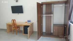 Habitación con escritorio, TV y armario de madera. en Nhà nghỉ 377, en Bao Loc