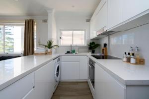 cocina blanca con fregadero y lavavajillas en Manly Beachfront Apartment en Sídney