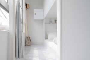 a white hallway with a bed and a window at Casa Blanca Guesthouse in Nagasaki