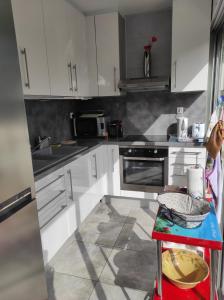 a kitchen with white cabinets and a red stool at 2 pièces avec grande terrasse in La Ciotat