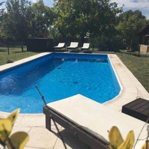 a swimming pool with chairs in a yard at Cabaña del Pedemonte in Ciudad Lujan de Cuyo