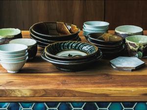 a group of bowls and plates on a wooden table at CHULAX OKINAWA YOMITAN【Designer Condominium Hotel】 in Yomitan