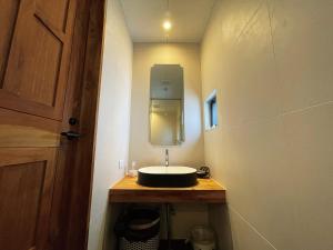 a small bathroom with a sink and a mirror at CHULAX OKINAWA YOMITAN【Designer Condominium Hotel】 in Yomitan