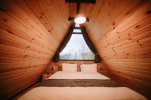 a bed in a wooden room with a window at Hilltop Batumi in Batumi