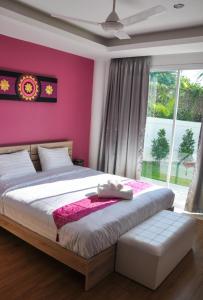 1 dormitorio con 1 cama grande y pared de color rosa en The Inspiration Residence, en Rawai Beach