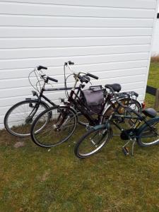 3 vélos garés dans l'herbe à côté d'une maison dans l'établissement AMELAND - Ballum: Stacaravan Chalet (incl. fietsen) bij strand en zee, à Ballum