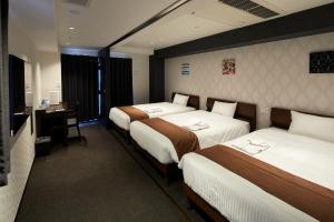 Habitación de hotel con 3 camas y escritorio. en HOTEL BRILLER Kyoto Station South, en Kioto