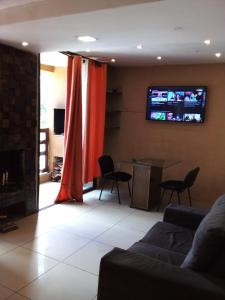 Una sala de estar con un sofá y un televisor en la pared. en N1 1 Apartamento Completo 2 Dormitorios en Centro de Artigas, en Artigas