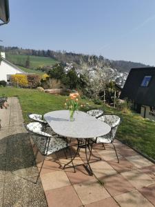 een tafel met stoelen en een vaas met bloemen op een patio bij Ferienwohnung und B&B Chasa Janett in Rudolfstetten