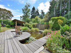 a wooden deck with a chair and a pond at Villa Sylvania in Spa