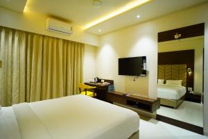 Habitación de hotel con 2 camas, escritorio y TV. en Orange Tree Hotels en Nagpur