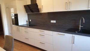 a kitchen with white cabinets and a black counter top at HAUS WALD und SEE - WASSERBURG in Wasserburg am Bodensee