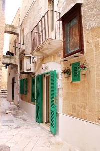 un edificio con persianas verdes y una ventana en La casetta del cuore, en Monopoli