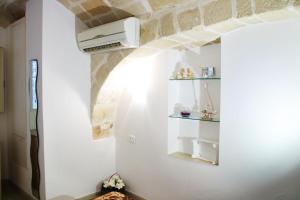Habitación con una pared blanca con calentador y estanterías en La casetta del cuore, en Monopoli