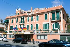 a large pink building with flags on a street at Rex Hotel Residence in Genoa