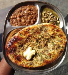 eine Person, die einen Teller Essen mit einer Pizza hält in der Unterkunft swaran House in Amritsar