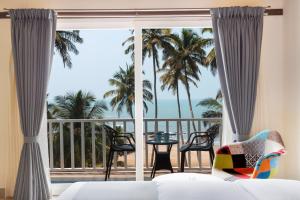 a bedroom with a bed and a balcony with palm trees at Stone Wood Beach Resort, Vagator in Vagator
