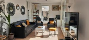 a living room with a black couch and chairs at TERRASSES PARC NATIONAL DES CALANQUES-SORMIOU in Marseille