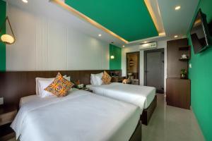 two beds in a room with green and white at AnNam68 in Hoi An