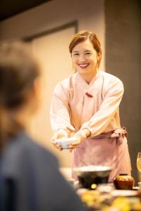 a woman standing in a kitchen holding a plate at Komatsuya Hachinobou in Izunokuni