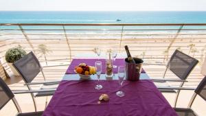 a table with a purple table cloth on a balcony with the beach at Playa Norte 7ºG in Peniscola