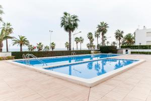 a swimming pool in a resort with palm trees at Playa Norte 7ºG in Peniscola