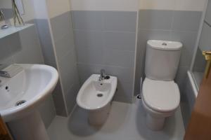 a white bathroom with a toilet and a sink at La Caparina, apartamento con piscina a 3 km de la playa in Llanes