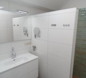 a white bathroom with a sink and a mirror at B&B de Scherpenhof, landelijk gelegen met optie jacuzzi in Leur