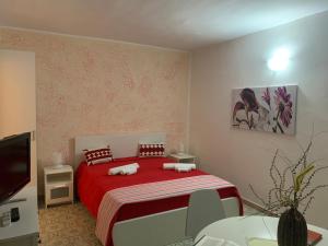 a bedroom with a red bed and a tv at Eden MONOLOCALE Torre dell Orso in Torre dell'Orso