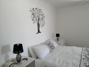 a bedroom with a white bed with a tree on the wall at T & T Thiart Fisherman's House in Dwarskersbos