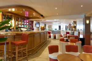 a bar in a restaurant with orange chairs and tables at Geographotel Paris-Roissy CDG Airport in Le Mesnil-Amelot