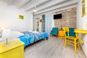 a bedroom with a bed and a desk and a yellow chair at Apartments & Rooms La casa Barbaro in Rovinj