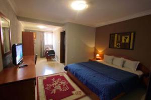a bedroom with a bed and a desk and a television at Room in Lodge - Carliza Hhotel-apapa in Lagos
