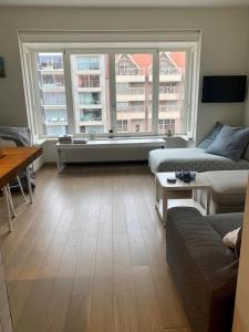 a living room with a couch and two windows at Appartement Giulia in Knokke-Heist