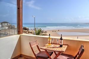 uma mesa e cadeiras numa varanda com vista para a praia em The Wave Baleal no Baleal