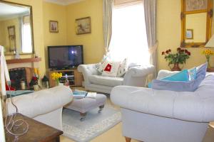 uma sala de estar com dois sofás brancos e uma televisão em Seaside Luxury House on the Suffolk Coast em Saxmundham