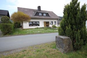 a white house with a tree and a road at Ferienhaus Marienweg in Hallenberg