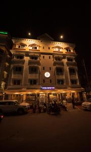 a large building with a clock on it at night at Rajdarbar Hotel & Banquet, Siliguri in Siliguri