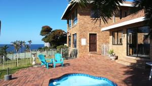 a house with a swimming pool and two blue chairs at Rockview Guest House in Port Edward