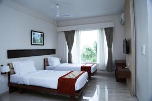 two beds in a hotel room with a window at Hotel Prism - A Boutique Hotel in Jorhāt +39 photos